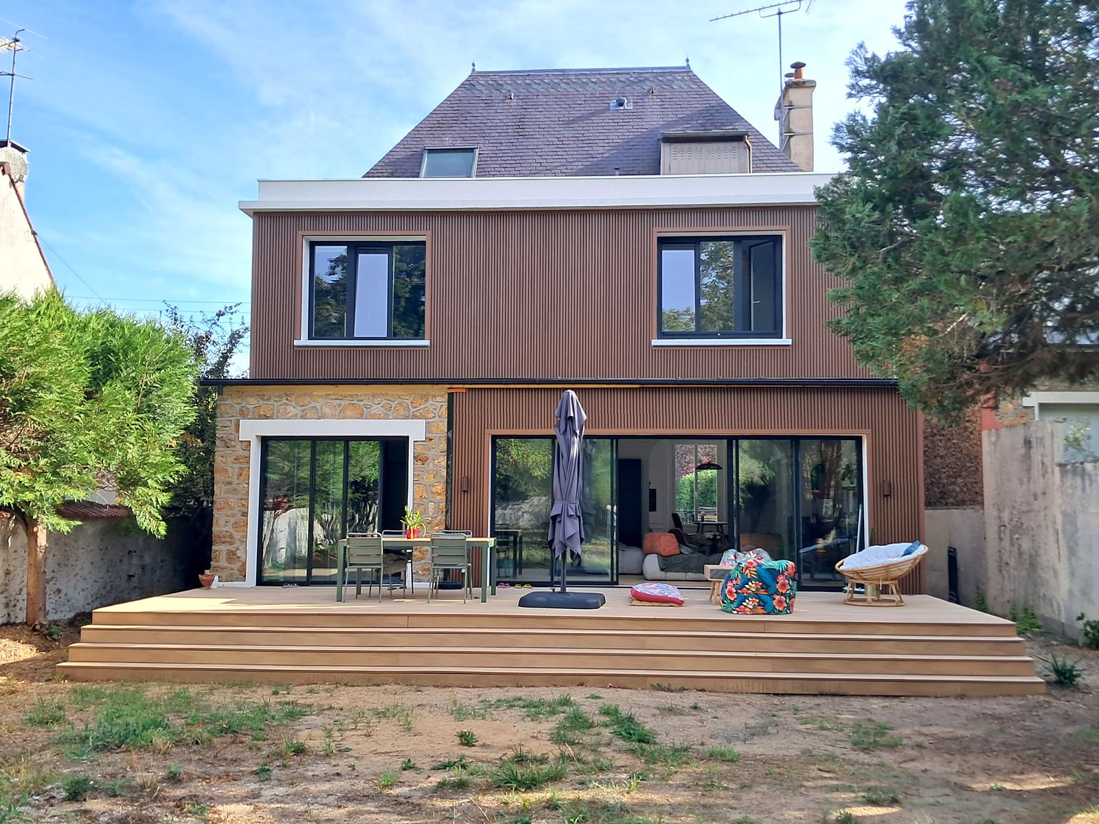 Pavillon en meulière après transformation : bardage bois vertical, grandes baies et terrasse